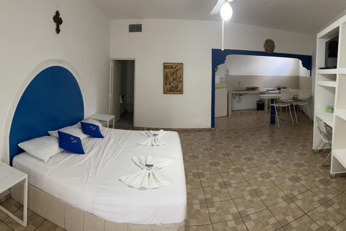 Ein Hotelzimmer mit Bett, kleinem Tisch, Küchenzeile und Essbereich.