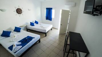 A hotel room with two beds, a desk, a TV, and a ceiling fan.