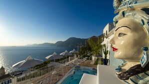 A poolside area with a view of the sea, umbrellas, and a statue. - Villa Aisha Private jacuzzi pool in Praiano (Praiano)
