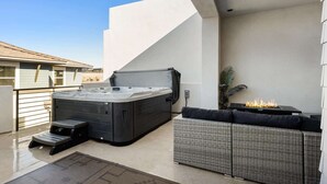 Eine Dachterrasse mit Whirlpool, Sitzgelegenheiten im Freien und einer Feuerstelle.