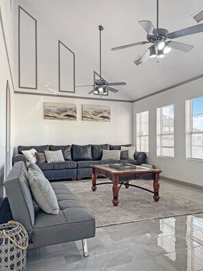 A modern living room with a sectional sofa, a wooden coffee table, and a ceiling fan. - "Lake house w/Mountain views” near River & Casinos (Bullhead City)