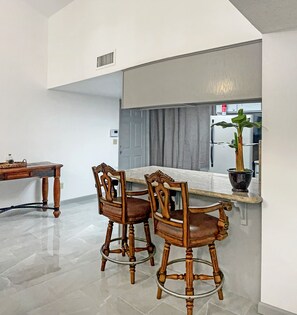 A kitchen with a marble countertop, two wooden bar stools, a potted plant, and a refrigerator in the background. - "Lake house w/Mountain views” near River & Casinos (Bullhead City)