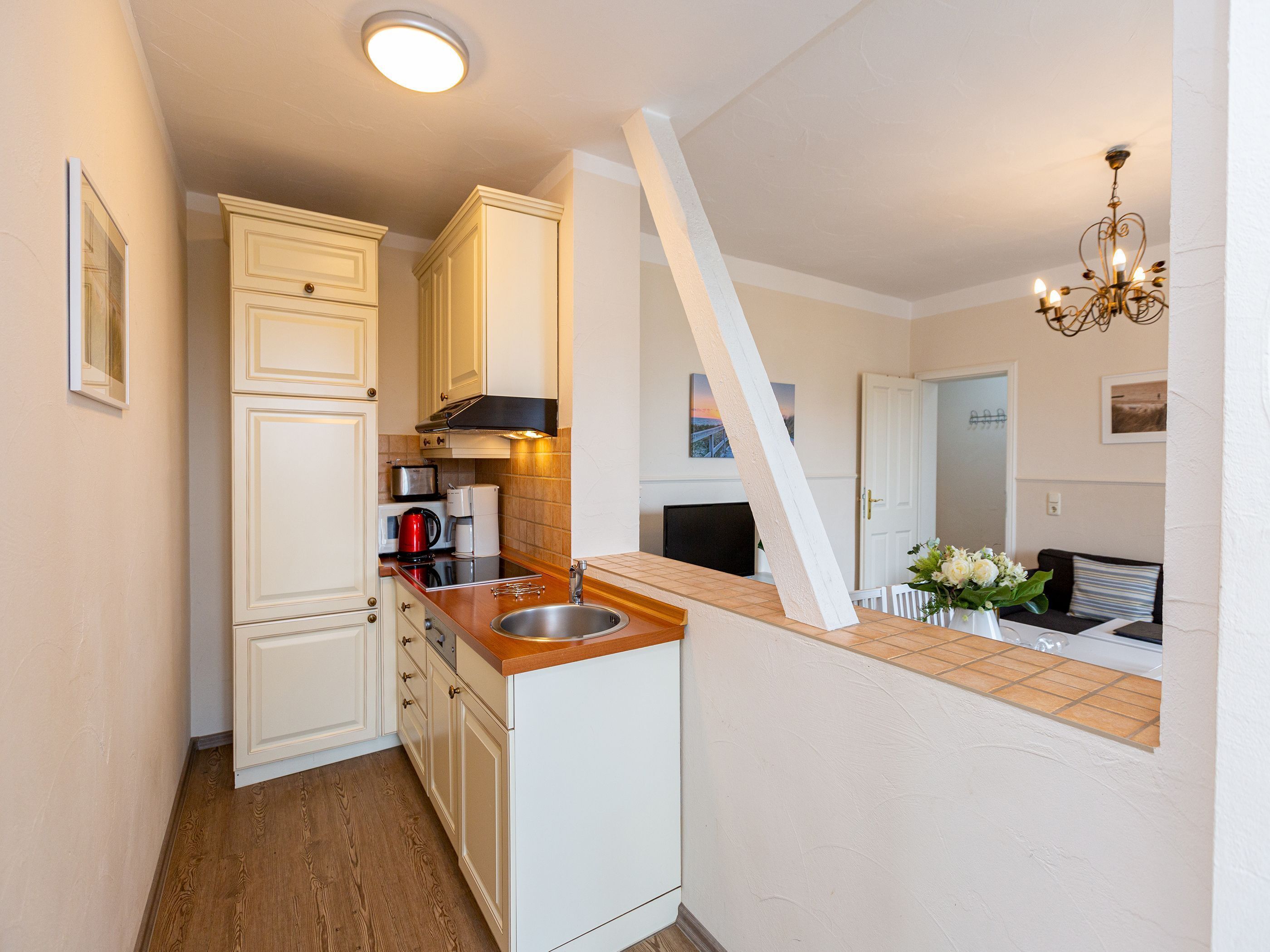 A compact kitchen with white cabinetry, a wooden countertop, and a built-in sink.