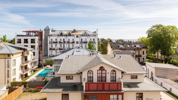 Ett hotell med flera våningar, en swimmingpool, balkonger och utsikt över havet.
