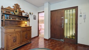 Un pasillo con un armario de madera, una puerta con panel de vidrio y suelo de baldosas.
