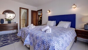 Una habitación de hotel con una cama, un aparador, un espejo y una puerta que da a otra habitación.