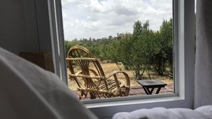 A room with a large window overlooking an outdoor area with a wicker chair and a small table.
