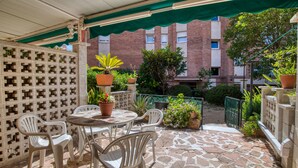 A patio with stone flooring, white plastic chairs, a round table, and potted plants. - Pet-Friendly 'Nice Apartment with Terrace' & Wi-Fi (Lloret de Mar)