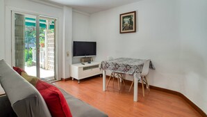 A living room with a sofa, a dining table, a TV, and a sliding glass door leading to a balcony. - Pet-Friendly 'Nice Apartment with Terrace' & Wi-Fi (Lloret de Mar)