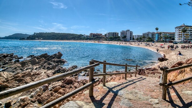 A coastal beach with a rocky shoreline, wooden railings, and buildings in the background. - Pet-Friendly 'Nice Apartment with Terrace' & Wi-Fi (Lloret de Mar)