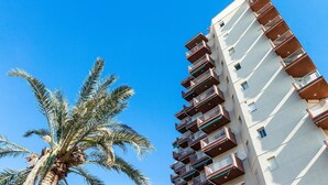A high-rise building with multiple balconies and a palm tree in the foreground. - Apartment "Las góndolas playa" with sea views, shared pool and Wi-Fi (Almunecar)
