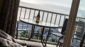 A balcony with a glass table, a bottle of wine, and two wicker chairs. - Apartment "Las góndolas playa" with sea views, shared pool and Wi-Fi (Almunecar)