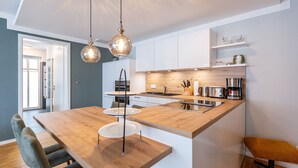 Eine moderne Küche mit Kochinsel aus Holz, Pendelleuchten und weißen Schränken.