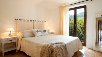 Quarto com cama, duas mesas de cabeceira, um criado-mudo, varanda e vista, além de uma porta.