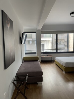 Una habitación moderna y luminosa con una cama, un sofá y un televisor montado en la pared.