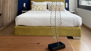 A modern bedroom with a bed, bedside tables, a decorative metal sculpture, and a large window. - Iasonos Suites (Athens)