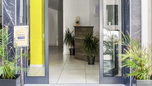 A hotel entrance with a reception desk, potted plants, and a sign indicating the hotel name. - Iasonos Suites (Athens)