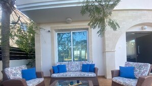 A patio area with wicker furniture, including two sofas and a coffee table, and a glass-top table. - Villa Sirena - Pernera (Paralimni)