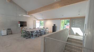 A spacious conference room with a long table, chairs, a projector, and a whiteboard with directional signs.