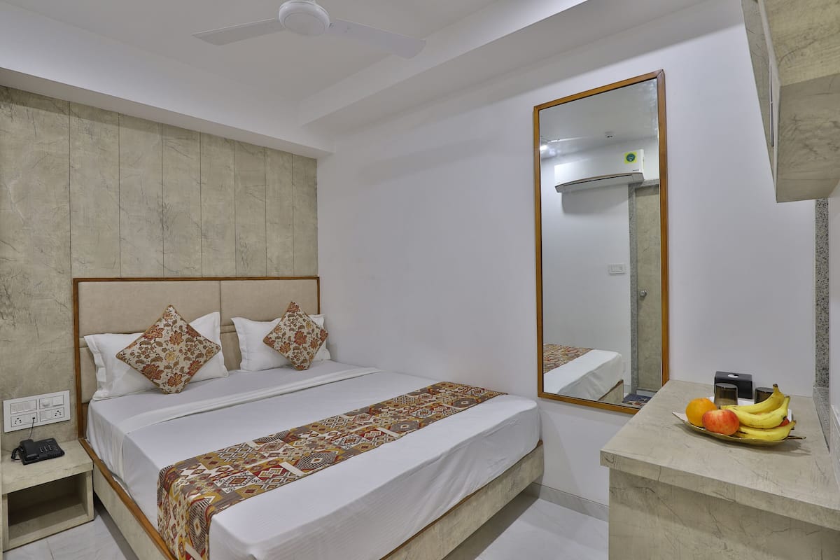 A hotel room with a bed, bedside table, and a mirror.
