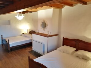 A bedroom with two single beds, a wooden dresser, a mirror, and a ceiling light.