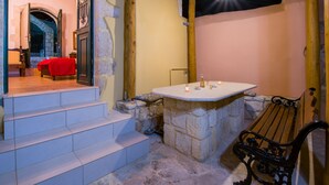 A stone-walled bathroom with a wooden bench, a sink, and a red chair. - Skandalis Apartment with pool view (Theano) (CHORAFAKIA CHANIA)