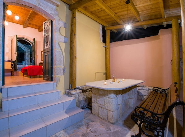 A stone-walled bathroom with a bench, a sink, and a mirror.