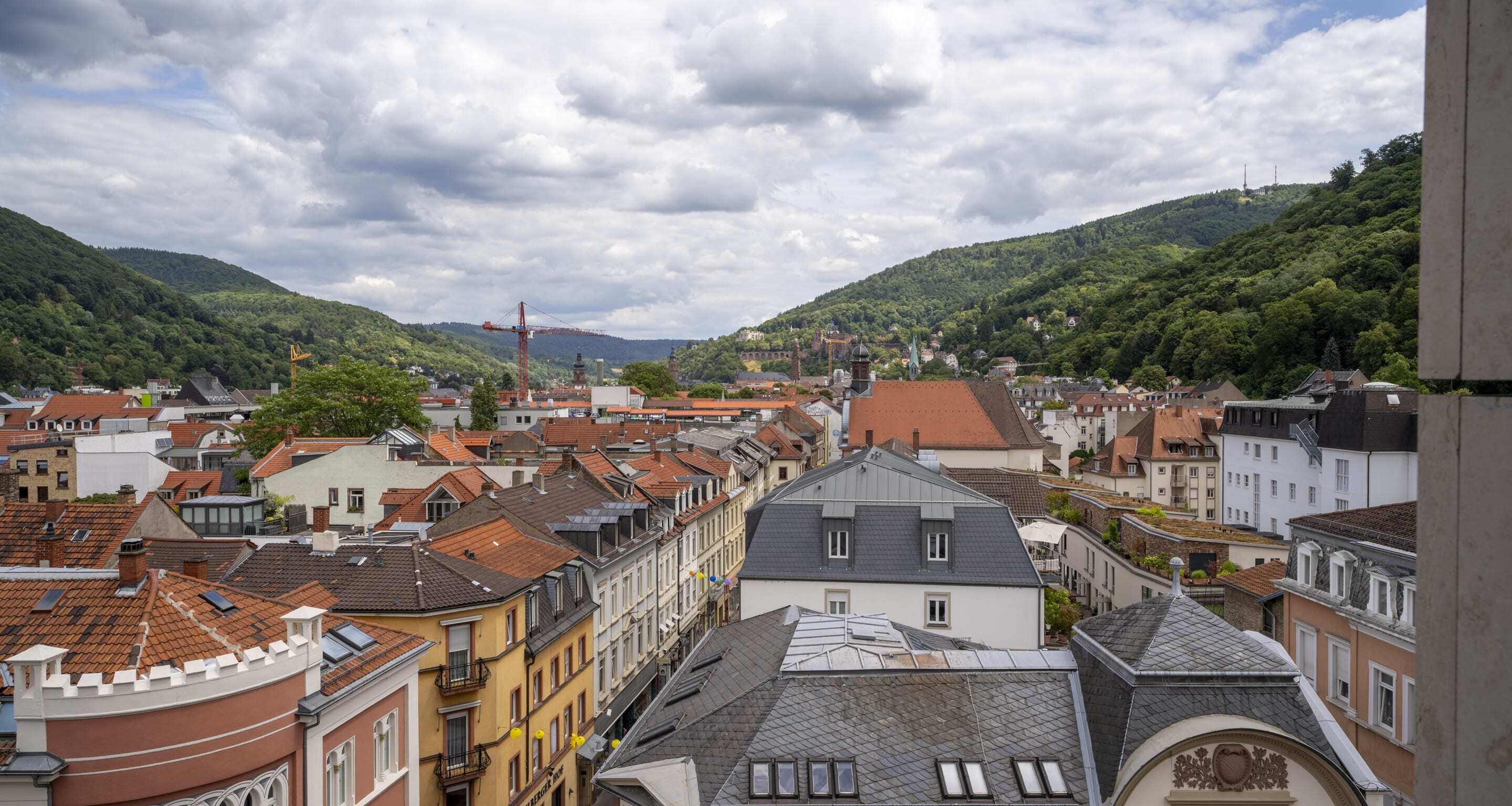 A town with historic buildings, a prominent church tower, and a hill in the background.