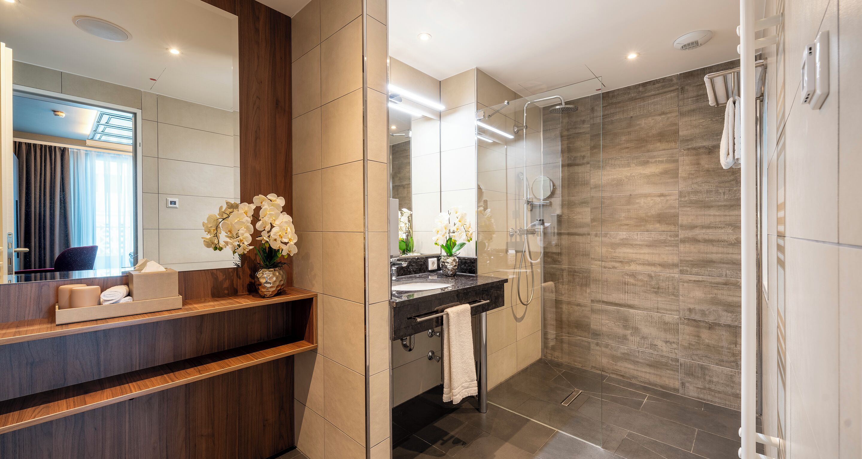 Une salle de bain moderne avec un meuble-lavabo en bois, une cabine de douche en verre et un grand miroir.