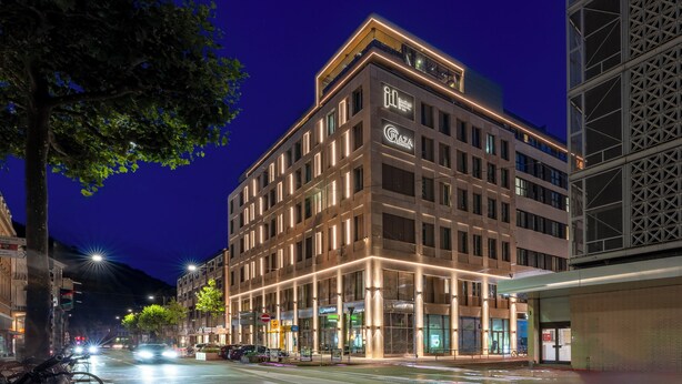 Un hotel de varios pisos con señalización iluminada, una entrada destacada y un diseño arquitectónico moderno.