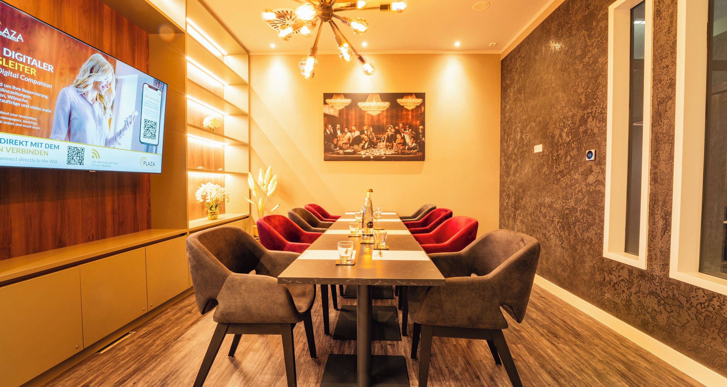 A modern dining area with a long table, multiple chairs, and a television screen displaying an advertisement.