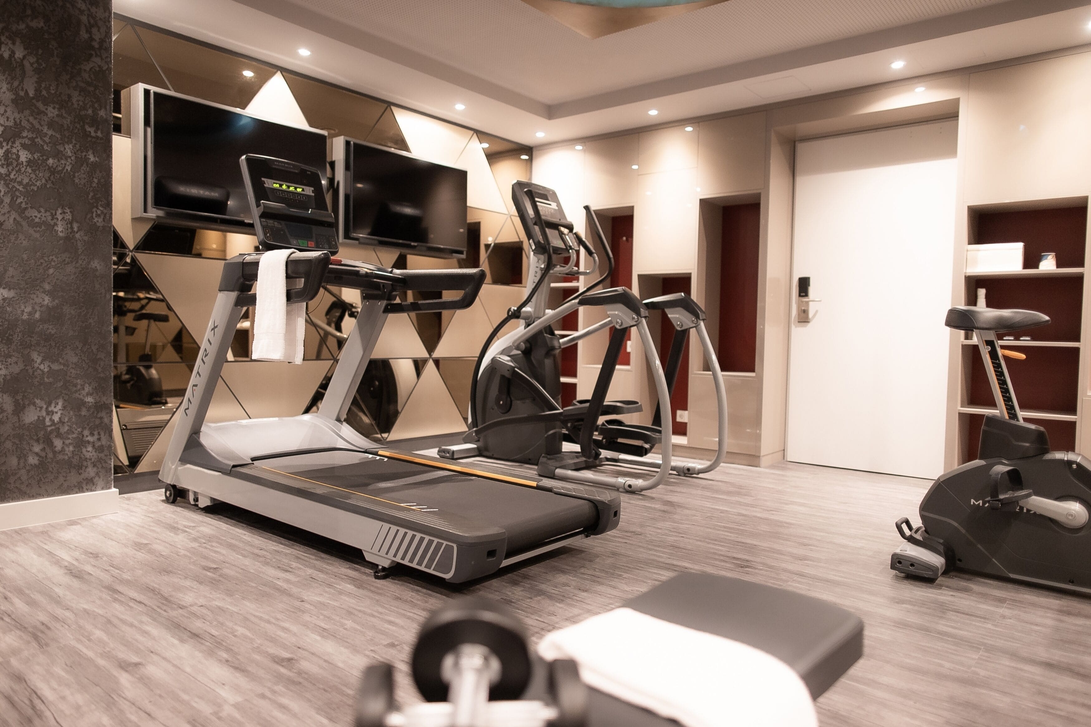 A modern gym with treadmills, elliptical machines, and a weight bench.