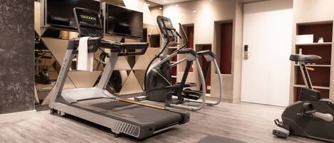 A modern gym with treadmills, elliptical machines, and a weight bench.