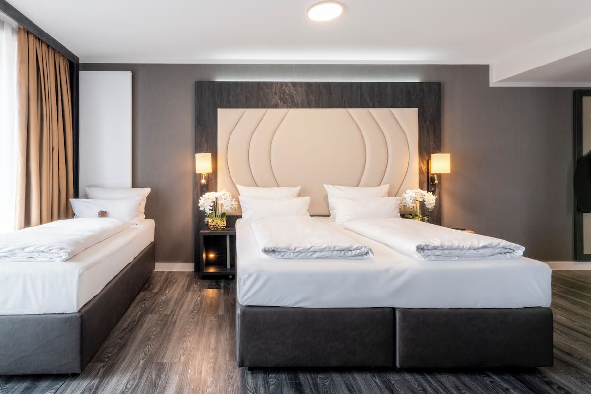 A hotel room with two single beds, a large bed, and a mirror.