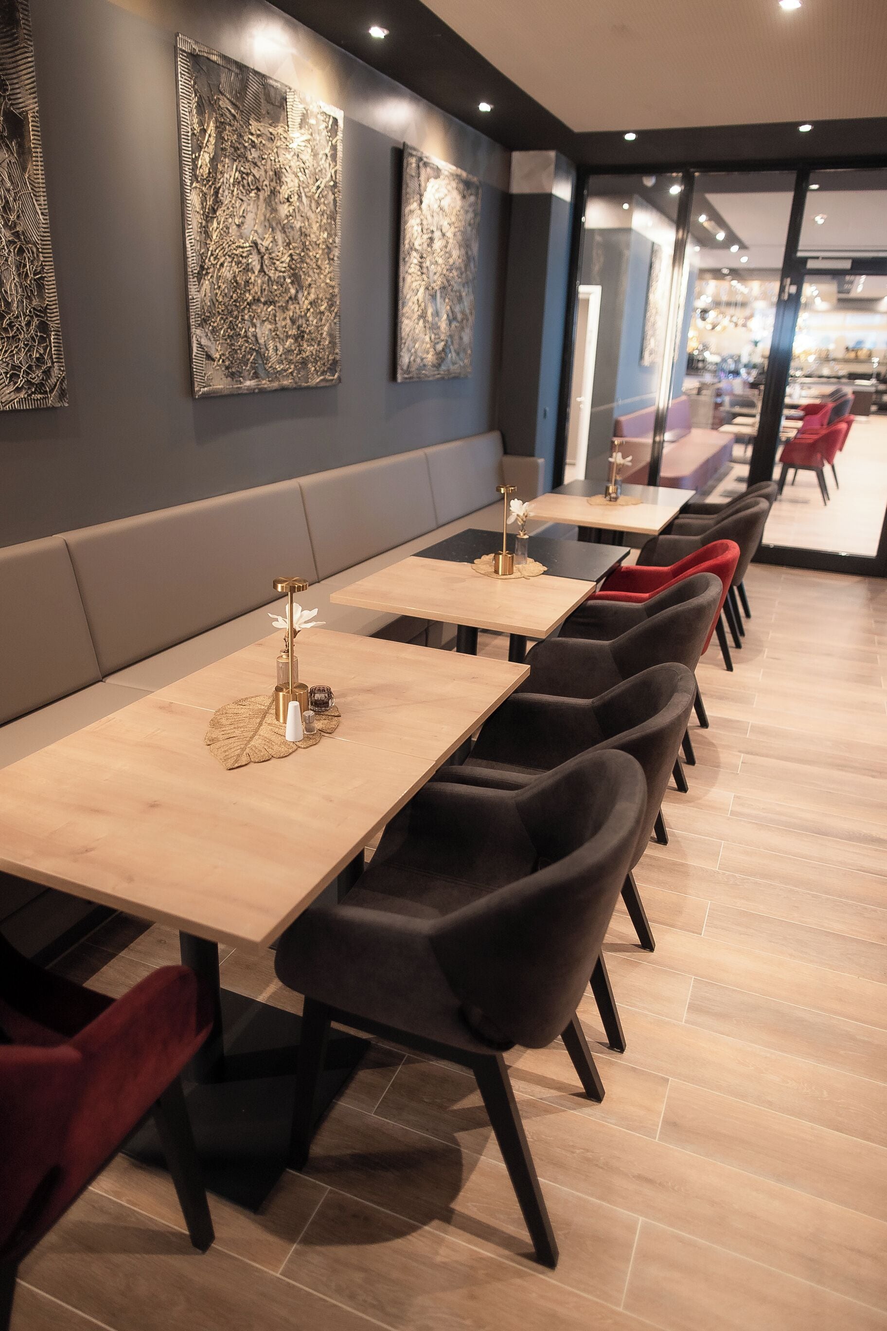 A modern restaurant with long tables and cushioned booths, featuring abstract wall art and a clean, contemporary design.