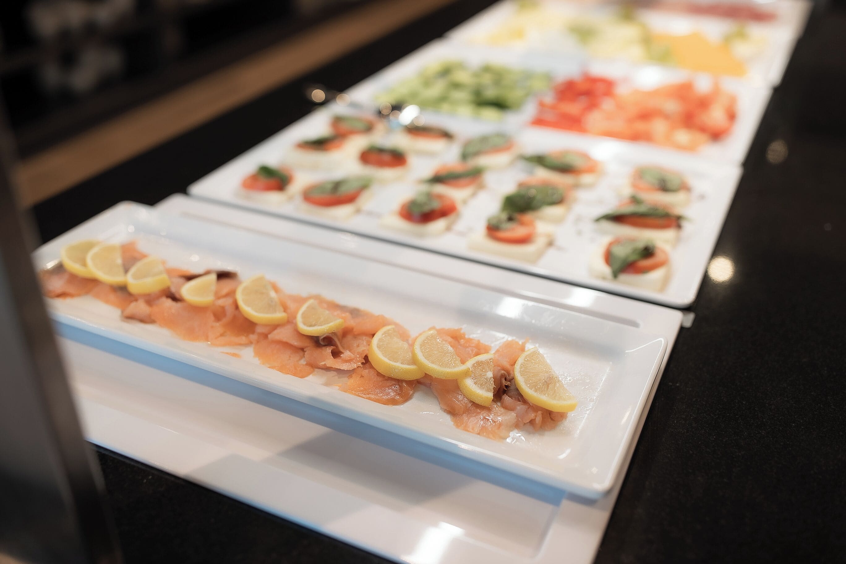 Un bufé con diversos alimentos, incluyendo salmón y otros platos.