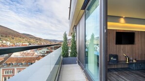 Habitación de hotel moderna con un amplio balcón de vidrio, televisor de pantalla plana y minibar.