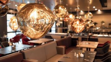 A restaurant interior with round, reflective hanging lights, cushioned seating, and a modern design.