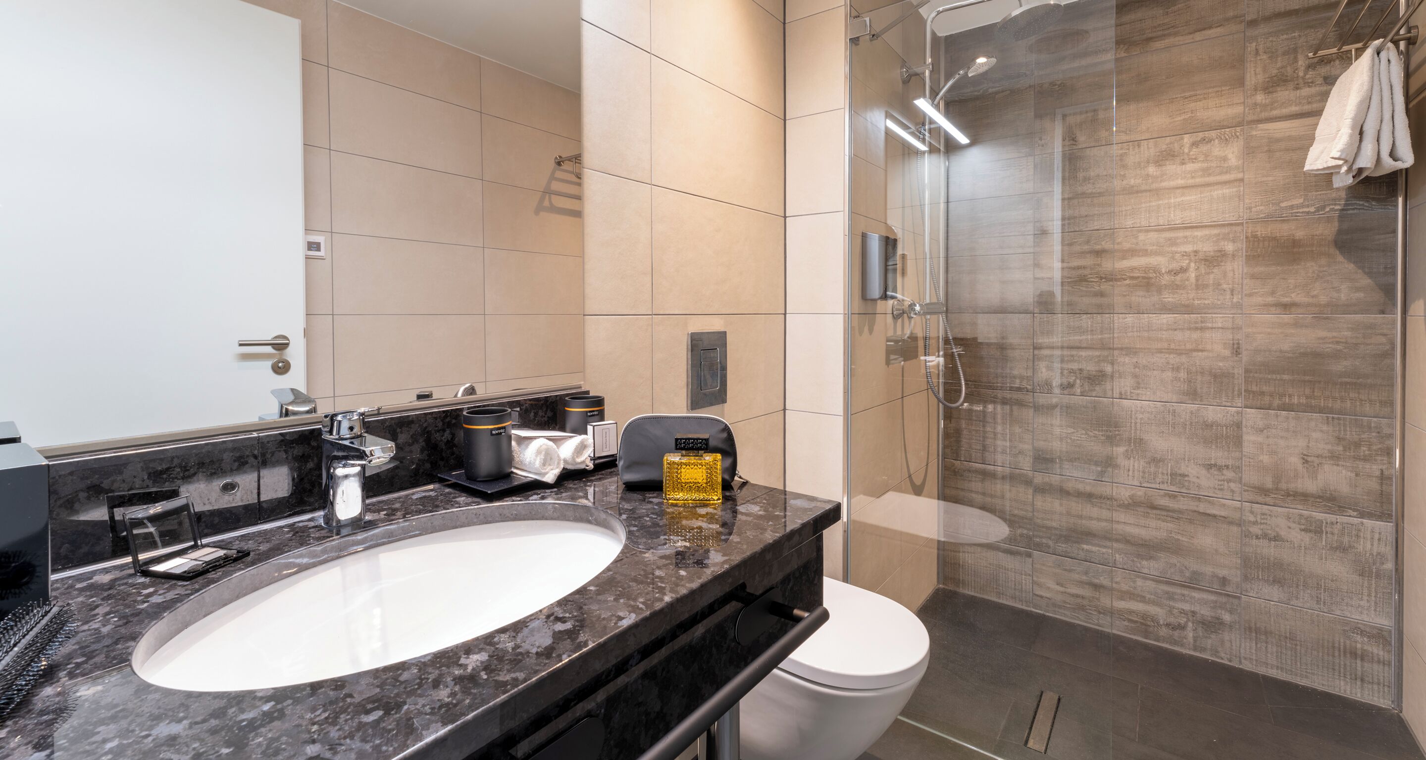 A modern bathroom with a large sink, mirror, and shower area.