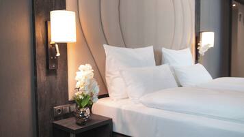 A hotel room with a large bed, a nightstand with a lamp, and a vase with flowers.
