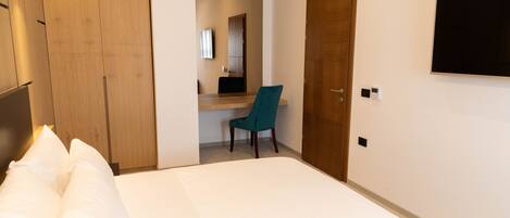 Una habitación de hotel con cama, escritorio, silla, televisor y armario.