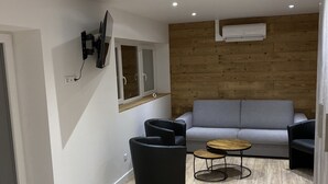 A modern living room with a grey sofa, black armchairs, a yellow ottoman, and a wooden coffee table. - CHALET ROMANE, SLEEPS 6, LAKE VIEW, AIR-CONDITIONED, BALCONY, MOTORCYCLE ROOM, GERARDMER (Gérardmer)