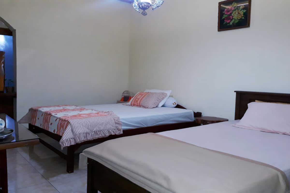 Una habitación con dos camas individuales, una mesita y una repisa en la pared.