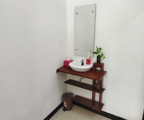 A bathroom with a white sink, a mirror, a small potted plant, a red soap dispenser, and a trash bin. - Borobudur Cluster Homestay Candirejo Syariah (Borobudur)