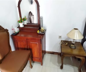 A wooden vanity with a mirror, a small table with a lamp, and a chair. - Borobudur Cluster Homestay Candirejo Syariah (Borobudur)