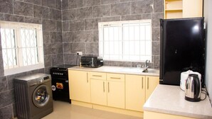 Cocina compacta con lavadora, estufa, microondas y refrigerador.