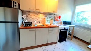 A modern kitchen with white cabinets, a stainless steel refrigerator, a dishwasher, and a window providing natural light. - Vacation apartment in a quiet location for 2 people (non-smoking property) (Born)