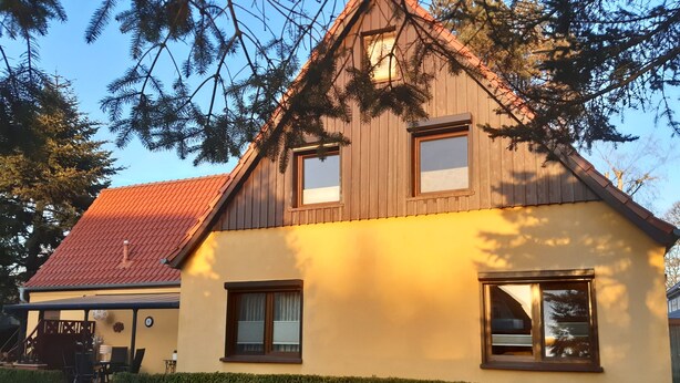 A two-story house with a red-tiled roof, wooden siding, and a yellow exterior. - Vacation apartment in a quiet location for 2 people (non-smoking property) (Born)