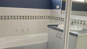 A bathroom with a bathtub, a sink, and a window.
