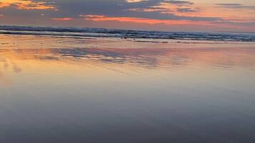 Una playa con agua tranquila que refleja el cielo.